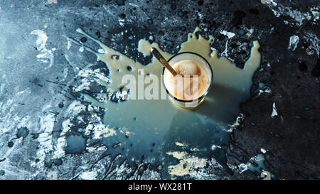 Il caffè freddo con il latte con cubetti di ghiaccio con schizzi su un calcestruzzo nero lo sfondo con spazio per il testo. Vista superiore Foto Stock