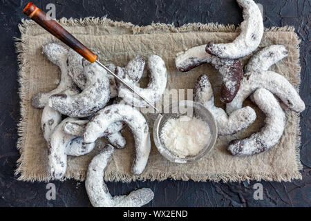 Biscotti al cioccolato a forma di mezzaluna e un filtro con zucchero a velo. Foto Stock