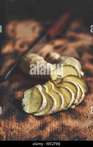 Lo zenzero, tagliati a fette, cucina, scheda close up, stile rustico Foto Stock