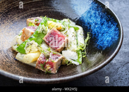 Moderno tonno fritto tataki di pesce filetto di manzo con insalata di asparagi bianchi zucchero scatta e parmigiano come vista dall'alto su una piastra Foto Stock