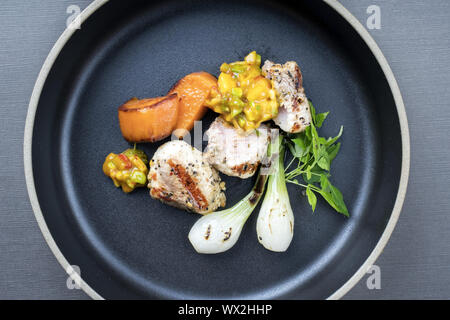 Del moderno barbecue di coda di coccodrillo occhio filetto arrosto con patate dolci e mango chutney di peperoncino come vista dall'alto su una piastra Foto Stock