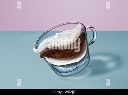 Separare gli strati volanti di caffè, latte, acqua e schiuma di latte nella bevanda di caffè in una coppa trasparente su un sfondo bicromatica. Foto Stock