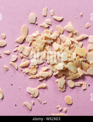 Fette di mandorla nell'heap su uno sfondo di colore rosa. Vista da vicino Foto Stock
