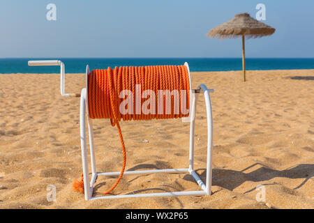 Linea di sicurezza sulla spiaggia con ombrellone e mare Foto Stock