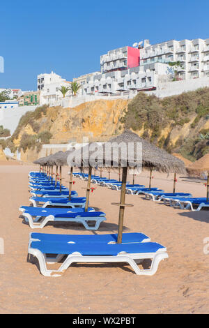 File di lettini da spiaggia con ombrelloni di paglia Foto Stock