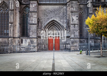 Imponente cattedrale gotica di Nostra Signora dell'assunzione di Clermont-Ferrand in Francia con la Rossa porta di legno, costruito da scure rocce vulcaniche Foto Stock