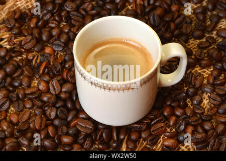 White tazza di caffè in chicchi di caffè in background. Foto Stock
