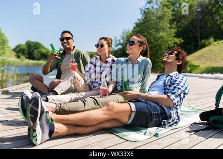 Gli amici a bere birra e sidro sul lago di pier Foto Stock