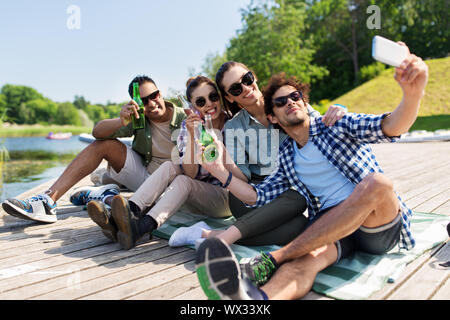 Amici con drink prendendo selfie tramite smartphone Foto Stock