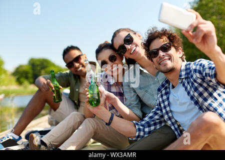 Amici con drink prendendo selfie tramite smartphone Foto Stock