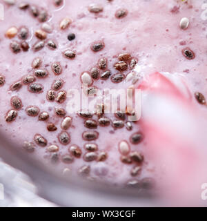 Foto macro appetitoso milky berry smoothie con organici chia semi in un bicchiere con una cannuccia. Dessert sano. Vista superiore Foto Stock