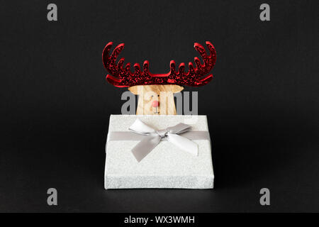 Decorazione di natale renne con argento Confezione regalo su uno sfondo nero con spazio per i tuoi contenuti Foto Stock