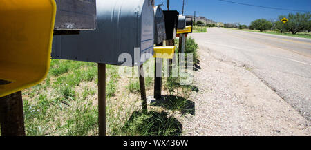 Riga di metallo e le cassette postali di plastica sul lato di un'autostrada in remoto Foto Stock