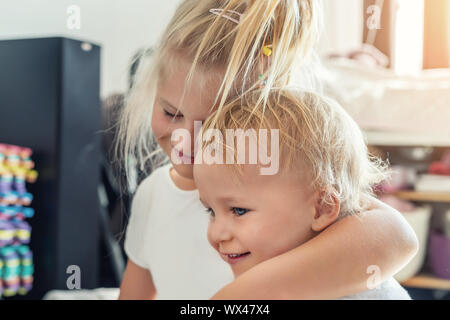 Carino adorabile bionda caucaian sorellina abbracciando il suo bimbo piccolo fratello.coppia di gemelli allegro giocando indoor. Ragazza carina e baby boy godere Foto Stock