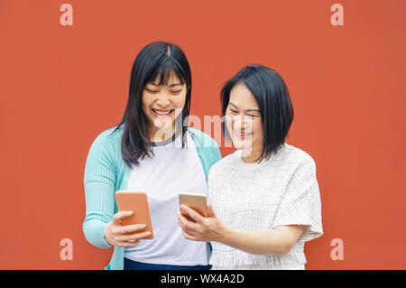 Asian madre e figlia utilizzando gli smartphone mobile outdoor - felice famiglia cinese per divertirti con le nuove tendenze della tecnologia app per i social media Foto Stock