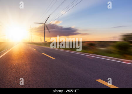 Le turbine eoliche sul paesaggio lungo la strada a vuoto contro sky Foto Stock