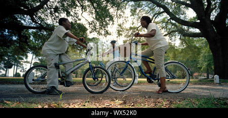 Mid-adulto madre e figlio seduti su biciclette e parlando in un parco all'aperto. Foto Stock