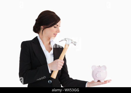 Imprenditrice andando a rompere una piggy-banca con un martello contro uno sfondo bianco Foto Stock
