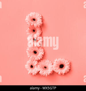 La lettera L realizzati dai fiori gerbera su un colore di sfondo dell'anno 2019 coralli viventi Pantone. Parte della parola amore. Vista dall'alto. Foto Stock