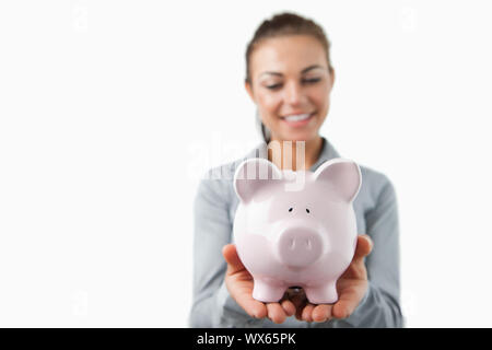 Salvadanaio essendo tenuto dalla banca femmina assistant contro uno sfondo bianco Foto Stock