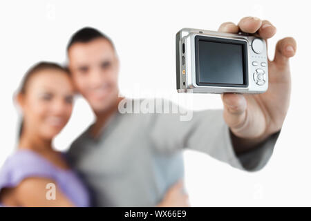 Fotocamera utilizzata per scattare una foto della coppia giovane contro uno sfondo bianco Foto Stock