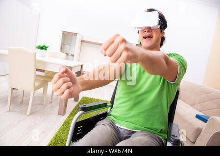 Giovane uomo bello in carrozzella a casa Foto Stock