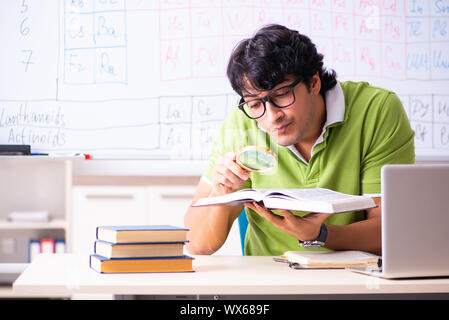 Giovane maschio chimico dello studente nella parte anteriore della tavola periodica Foto Stock