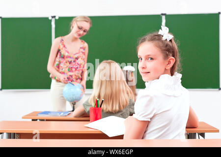 Ritratto della ragazza in classe, il Maestro dice al prossimo Consiglio scolastico Foto Stock