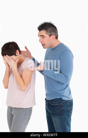 Donna che piange mentre il marito sta cercando di spiegare se stesso contro uno sfondo bianco Foto Stock