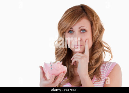 Biondo e premurosa donna mentre si tiene il suo rotto piggybank su sfondo bianco Foto Stock