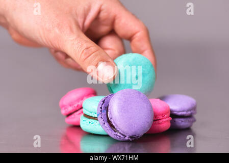 Mano maschio di prelevare un maccaron dalla tabella Foto Stock