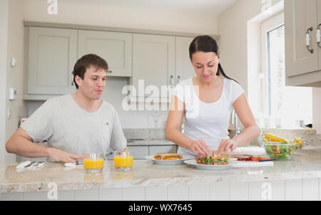 Due persone sono in cucina mentre uno di loro fa panini Foto Stock