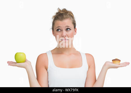 Donna azienda apple e Tortina di decidere di mangiare in modo sano o non Foto Stock