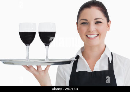 Felice cameriera tenendo due bicchiere di vino su un vassoio d'argento nella parte anteriore della fotocamera Foto Stock