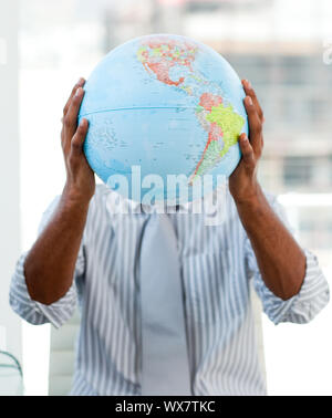 Afro-americane imprenditore tenendo un globo terrestre nel suo ufficio Foto Stock