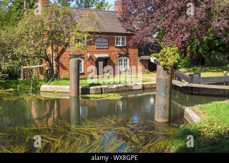 Vista di New Haw serratura e il blocco storico del portiere cottage sul fiume Wey (Wey navigazioni) a New Haw, Surrey, Inghilterra del sud-est Foto Stock