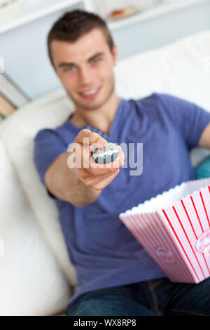 Uomo sorridente è rilassante nel salotto strega popcorn guardando la televisione Foto Stock