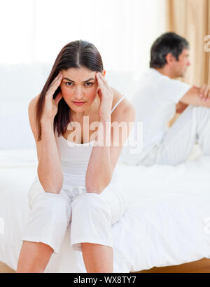 Triste giovane seduta seduta separatamente sul loro letto dopo aver una riga Foto Stock