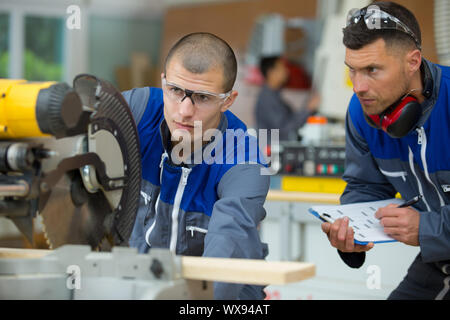 Giovane falegname utilizzando un pesante macchinari circolare Foto Stock