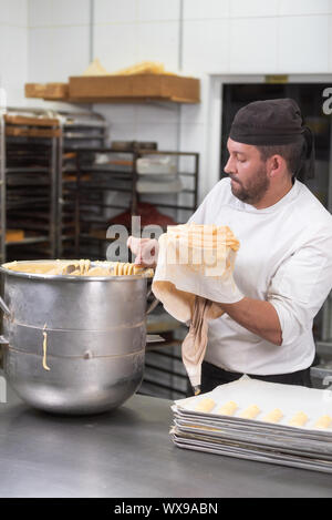 Pastry Chef con il sacchetto per la pasticceria la spremitura di crema alla pasticceria. Foto Stock