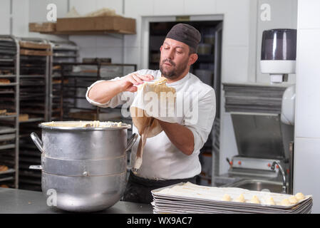 Pastry Chef con il sacchetto per la pasticceria la spremitura di crema alla pasticceria. Foto Stock