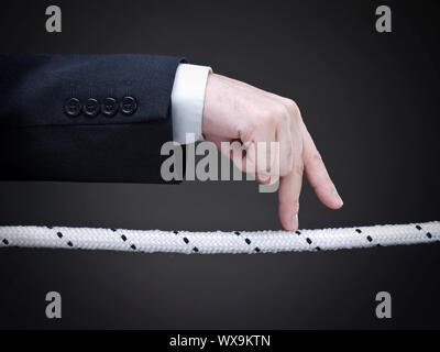 Close up di un imprenditore le dita di camminare sulla fune. Immagine concettuale. Foto Stock