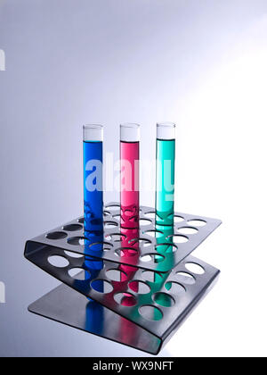 Tre provette riempite con liquidi colorati su una rastrelliera metallica. Foto Stock