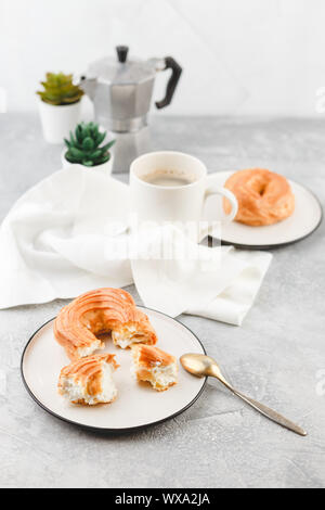 Soffio di crema anelli - bignè e tazza di caffè nero Foto Stock