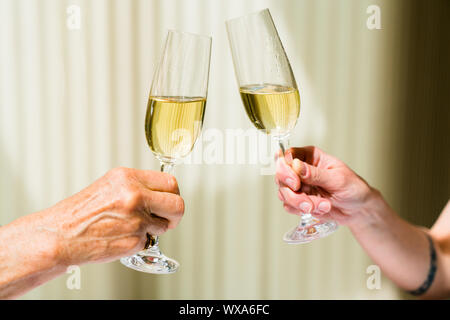 Mano di eldery donna e donna giovane la tostatura con bicchieri di champagne Foto Stock