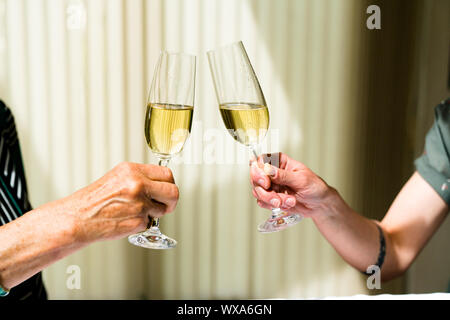 Mano di eldery donna e donna giovane la tostatura con bicchieri di champagne Foto Stock