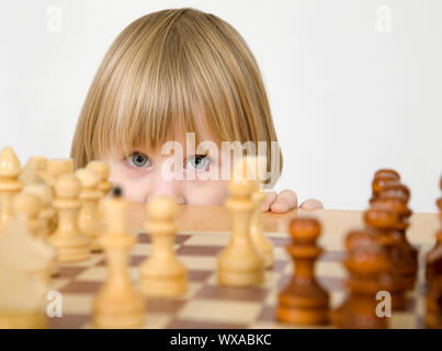 Bambina pigoli per il gioco degli scacchi su sfondo bianco Foto Stock