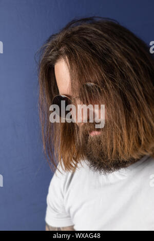 Barbuto giovane con i capelli lunghi e occhiali da sole Foto Stock