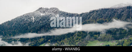 Vista panoramica del monte Pizalun nelle alpi svizzere con neve fresca nebbia e nuvole sopra il fo Foto Stock