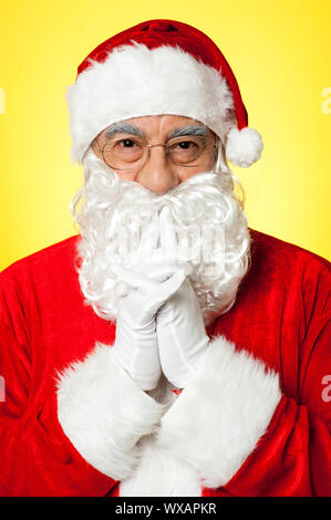 Riflessivo Santa Claus indossando occhiali,su sfondo giallo Foto Stock